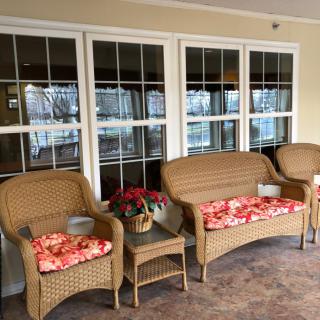 A cozy patio with wicker furniture and floral cushions, overlooking large windows.