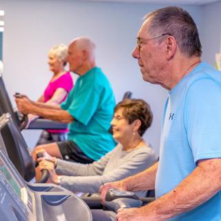 A group of seniors exercising on treadmills at the gym.