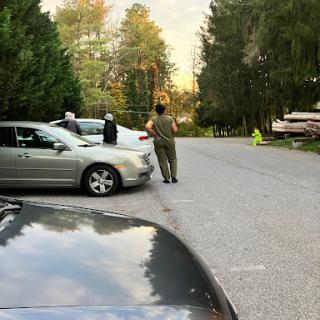 A quiet street scene with parked cars and a few individuals conversing.
