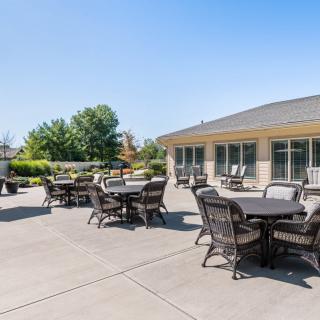 A sunny outdoor patio area with tables and chairs near a building.