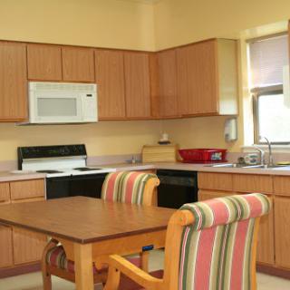 A cozy kitchen featuring wooden cabinetry, a dining table with striped chairs, and modern appliances.