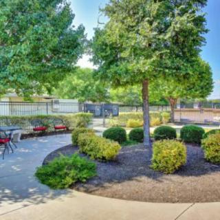 A peaceful garden with a pathway and outdoor seating surrounded by trees and bushes.