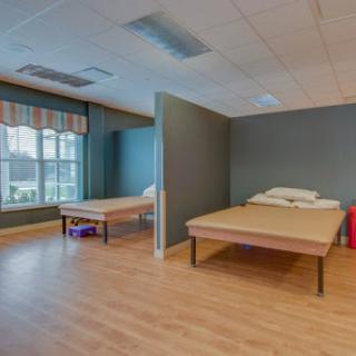 A clean and minimalistic hospital room featuring two unmade beds and ample natural light.