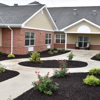 A well-maintained garden with a curved walkway leading to a brick building.