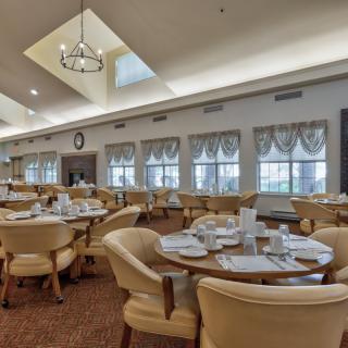 A well-lit dining room with neatly set tables and comfortable chairs.