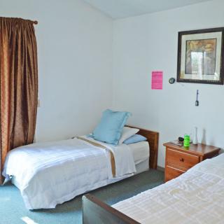 A simple bedroom with two beds and a nightstand.