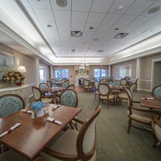 An elegant dining room with neatly arranged tables and chairs, featuring classic decor and ambient lighting.