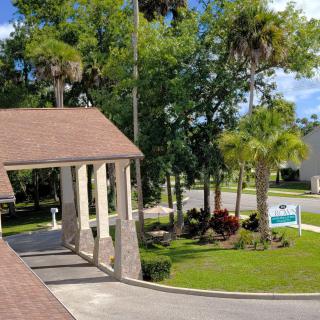 A view of a building with a covered driveway, surrounded by lush greenery and palm trees.