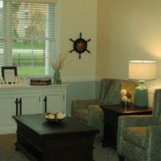 A cozy living room with comfortable chairs, a coffee table, and decorative elements like a lamp and wall decor.