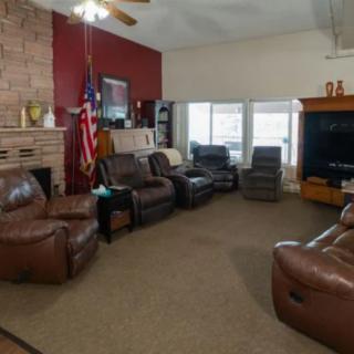 A cozy living room featuring leather sofas, a fireplace, a television, and an American flag.