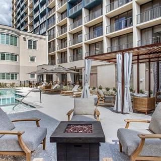 A modern outdoor hotel patio featuring a pool, lounge chairs, and a fire pit.