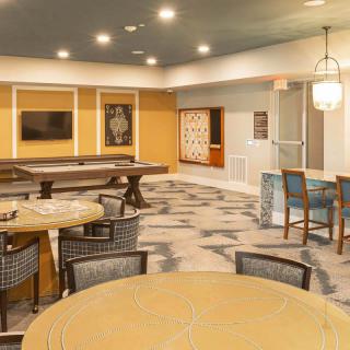 A modern lounge area with tables and chairs, decorated with stylish lighting and artwork.