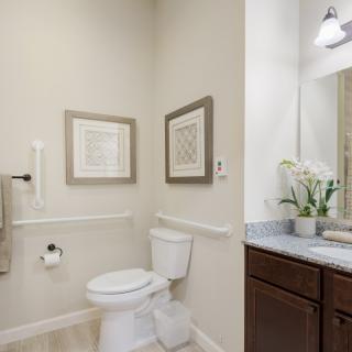A modern bathroom featuring a toilet, sink with mirror, and decorative wall art.