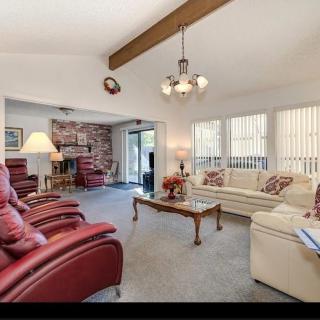 A cozy living room featuring comfortable sofas and armchairs, a coffee table, and large windows allowing natural light.