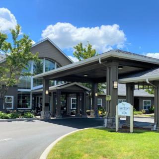 A large building with a covered entrance and scenic surroundings under a partly cloudy sky.