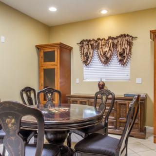 A traditional dining room featuring a wooden table and chairs, a cabinet, and decorative window treatments.