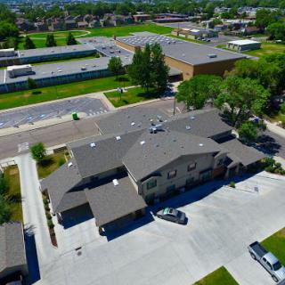 An aerial view of a residential building surrounded by green spaces and parking facilities.