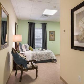 A cozy bedroom with a comfortable bed, stylish chair, and framed artwork on the walls.