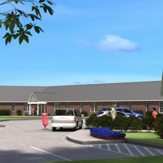 A parking lot in front of a long, single-story building with several cars parked under a clear blue sky.
