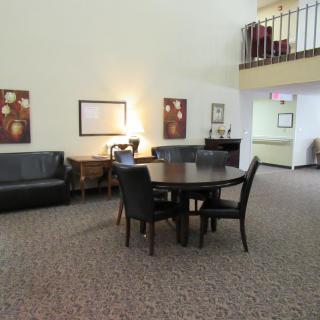 A cozy lobby area featuring a round table with chairs, a sofa, and decorative artwork on the walls.