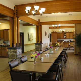A spacious dining area with a long table and chairs, complemented by wooden beams and chandeliers.