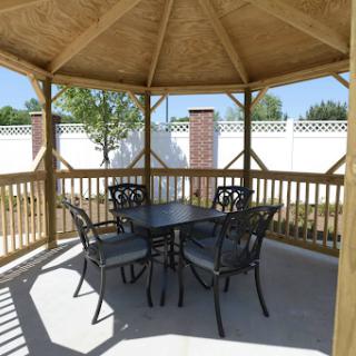 A cozy gazebo set up with a table and four chairs, perfect for enjoying outdoor gatherings.