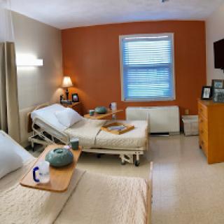 A well-lit hospital patient room featuring two beds and essential amenities.