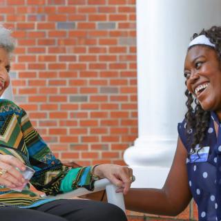 Two people enjoying a conversation on a porch.