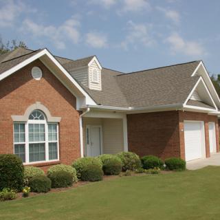 A suburban brick house with a well-maintained lawn and a two-car garage.