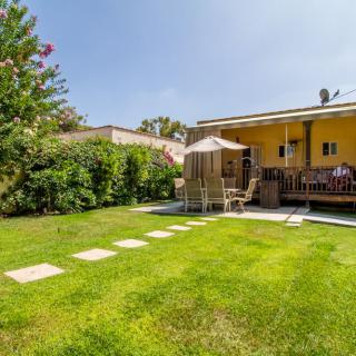 A charming backyard featuring a spacious lawn, patio with outdoor seating, and lush greenery.
