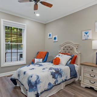 A cozy bedroom with elegant decor featuring a bed with floral bedding, a nightstand, and wall art.