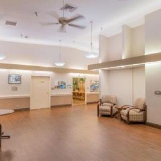 A spacious waiting room with comfortable seating and ceiling fans.