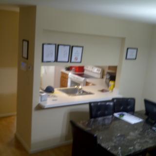 An open kitchen view from the dining area with a countertop and chairs.