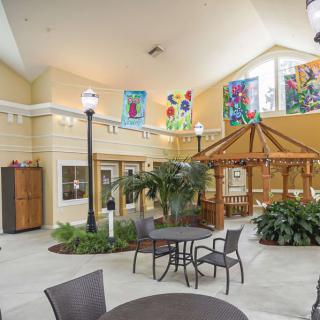 A bright indoor seating area with tables, chairs, plants, and colorful decorations.