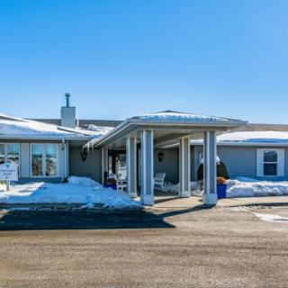 A sunny winter day at a building with snow on the ground and driveway.