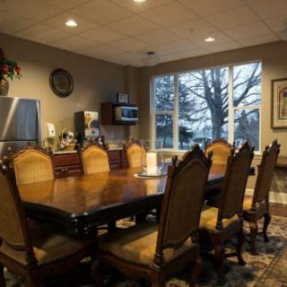 A formal conference room with a large table and chairs, featuring a window view.
