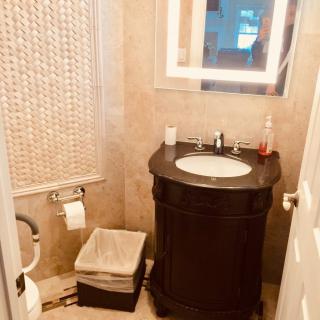 A compact bathroom with a tiled wall, featuring a sink, toilet, and mirror.
