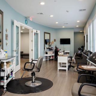 A modern and clean salon interior featuring chairs, mirrors, and a waiting area.