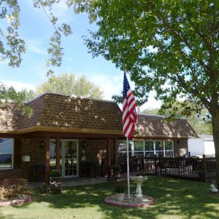 A charming house with an American flag in the front yard, surrounded by trees and a clear blue sky.