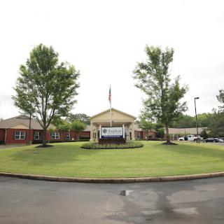 A well-maintained building with an American flag, surrounded by green grass and trees.