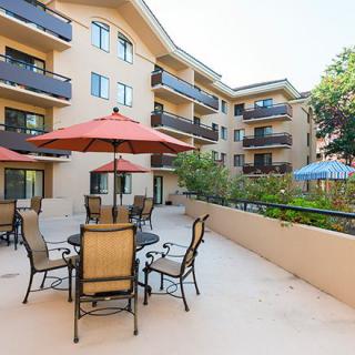 An outdoor patio area with tables, chairs, and umbrellas in a residential apartment complex.