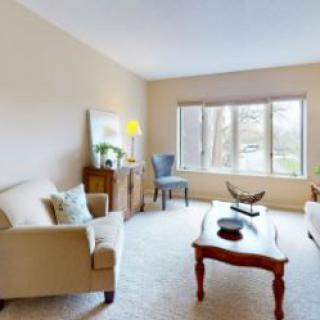 A cozy living room featuring comfortable sofas, a classic wooden coffee table, and large windows letting in natural light.