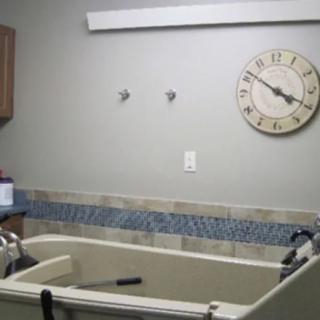 A modern bathroom featuring a bathtub, tiled wall, and a clock on the wall.