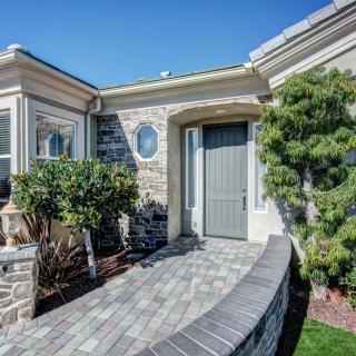 Charming house entrance with brick pathway and lush landscaping.