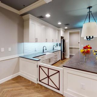 A modern kitchen with sleek countertops, pendant lighting, and light wood flooring.