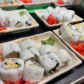 Plates of California rolls garnished with wasabi and pickled ginger.