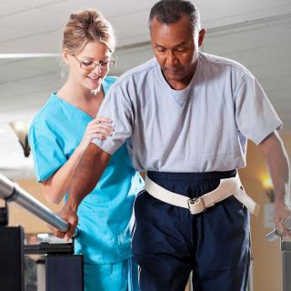 A nurse assists a patient during physical therapy.