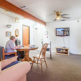 A spacious living room with a dining area, featuring a television and ceiling fan.