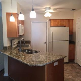 A modern kitchen featuring a granite countertop and pendant lighting.