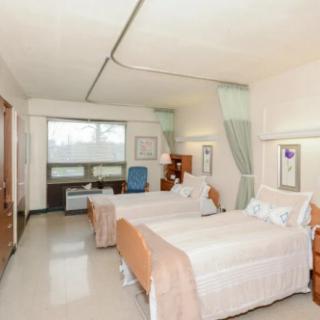 A hospital room with two beds, separated by a curtain, designed for patient care.